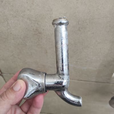 ברז מתכת מוחזק ביד על רקע קיר