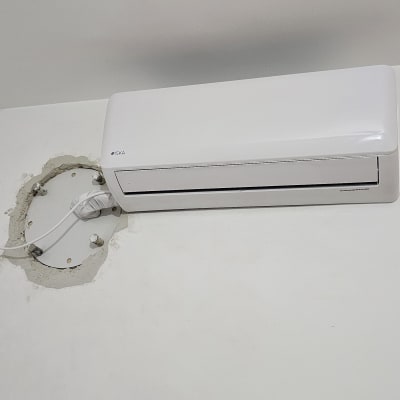 מזגן מותקן על קיר לבן עם חוטים חשופים