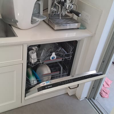 מדיח כלים פתוח עם כלים בפנים ליד מכונת קפה