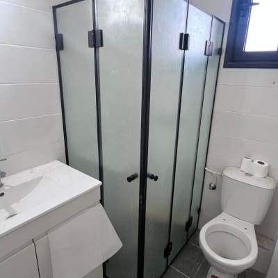 מקלחון זכוכית עם דלתות שחורות בחדר אמבטיה