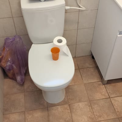 אסלה עם נייר טואלט וכוס על המכסה