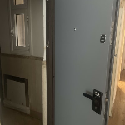 דלת אפורה פתוחה עם ידית שחורה ומנעול