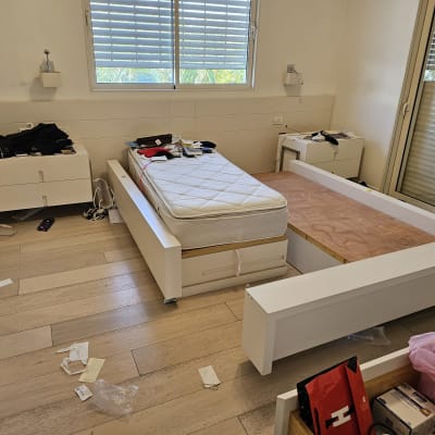 חדר שינה עם מיטה מפורקת וחפצים מפוזרים על הרצפה