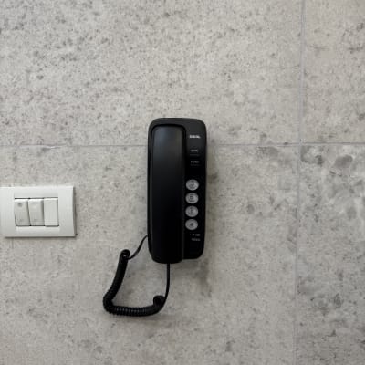 טלפון קווי מותקן על קיר עם מתגי חשמל