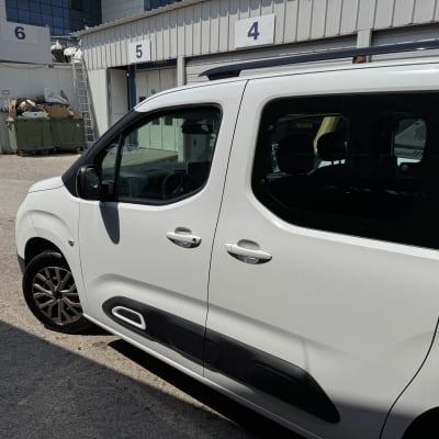 רכב לבן חונה ליד מבנה עם מספרים על הדלתות