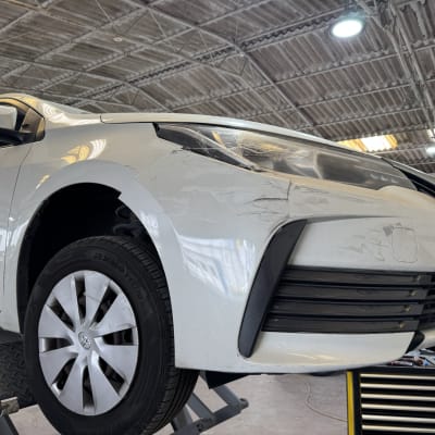 רכב לבן על מעלית במוסך עם סימני תיקון