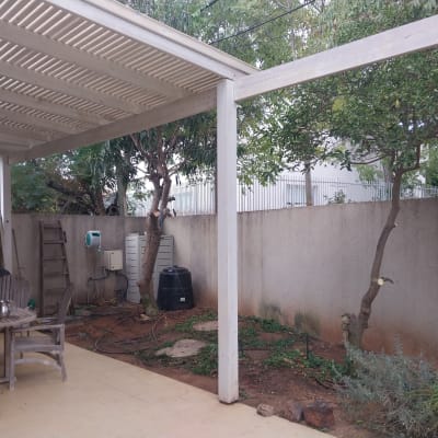 גינה עם עצים, שולחן וכיסאות תחת פרגולה