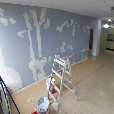 קיר צבוע חלקית עם סולם ודלי צבע