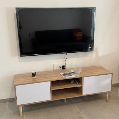 טלוויזיה תלויה על קיר עם שידה מתחת