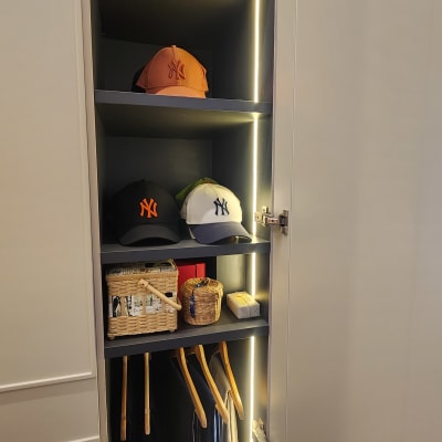 כובעים ומעילים מסודרים בארון מואר עם מדפים