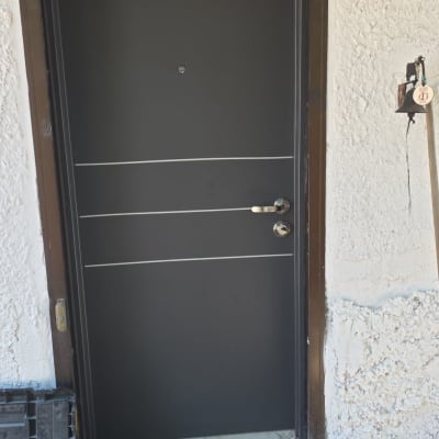 דלת מתכת כהה עם ידית כסופה וכלי עבודה על הרצפה