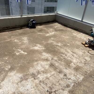 מרפסת עם רצפת בטון, דגלי ישראל תלויים, כלי עבודה בפינה