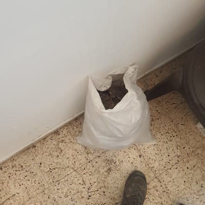 שקית לבנה עם פסולת על רצפה ליד קיר