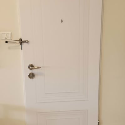 דלת לבנה עם ידית מתכת ובריח עליון