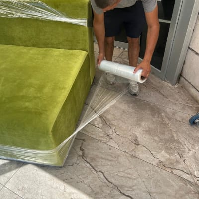 מוביל עוטף ספה ירוקה בניילון נצמד להגנה לפני הובלה