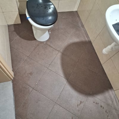 שירותים עם מושב רטוב ורצפה עם כתמי מים
