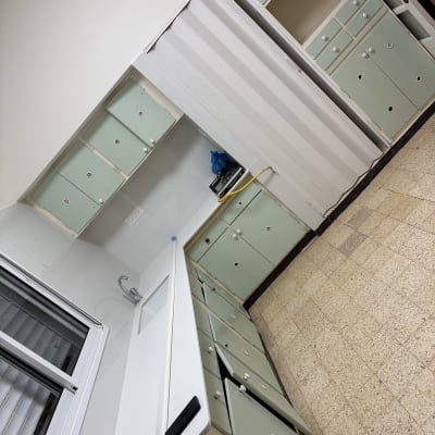 מטבח נקי עם ארונות ירוקים ומשטח עבודה לבן