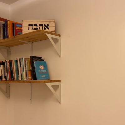 מדפים מעץ עם ספרים וקופסה על הקיר