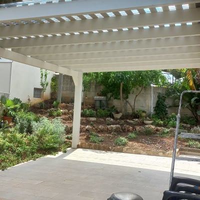 גינה עם צמחים מתחת לפרגולה לבנה