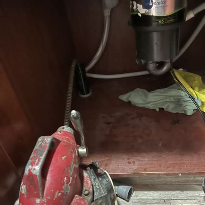 כלי עבודה מתחת לכיור עם צינורות ומכונת טחינה