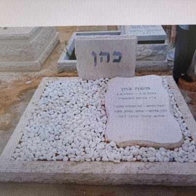 מצבה עם כיתוב בעברית ואבנים לבנות מסביב