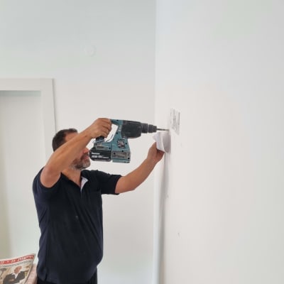 אדם קודח בקיר עם מקדחה חשמלית