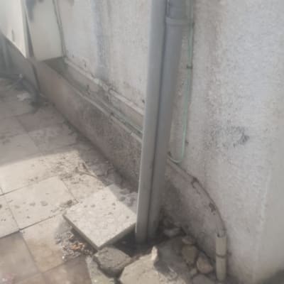 צינור ביוב אפור עם נזילה על רצפה רטובה