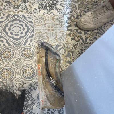 צינור שחור בתעלה ברצפה עם אריחים מעוצבים