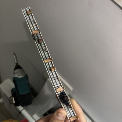 יד מחזיקה פסי נחושת וכלי עבודה חשמלי ברקע