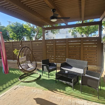 ריהוט גן תחת פרגולה עם כיסאות ושולחן