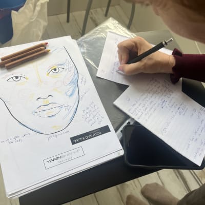 שרטוט פנים עם הערות וכלי איפור על שולחן