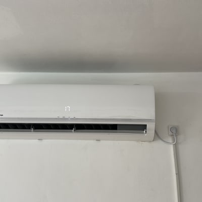 מזגן קיר לבן מותקן על קיר עם צינור חשמל