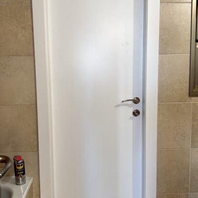 דלת לבנה עם ידית מתכת בחדר אמבטיה