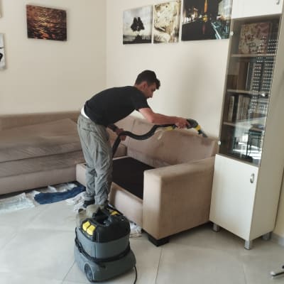 אדם מנקה ספה עם שואב אבק מקצועי