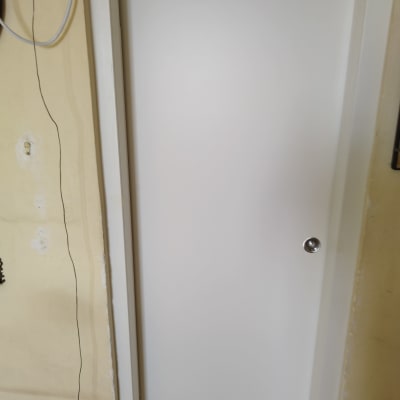 דלת לבנה עם ידית כסופה על קיר צהוב