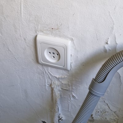 שקע חשמל בקיר עם צינור גמיש אפור