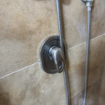 ברז מקלחת עם צינור מתכת על קיר אריחים