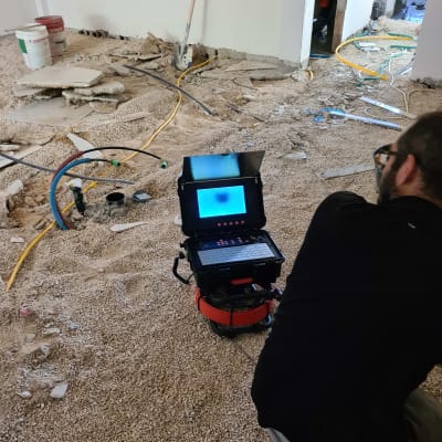 אדם משתמש במכשיר צילום תת קרקעי באתר בנייה