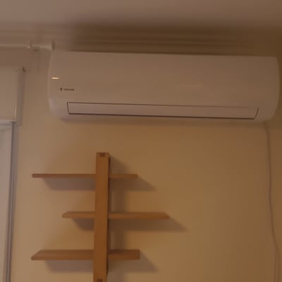מזגן מותקן על קיר בחדר עם מדף ועציצים