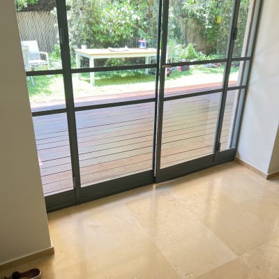 מרפסת עם דלת זכוכית ונוף לגינה ירוקה