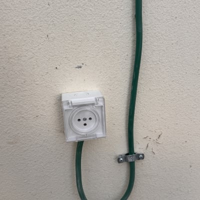 שקע חשמלי מותקן על קיר עם כבל ירוק