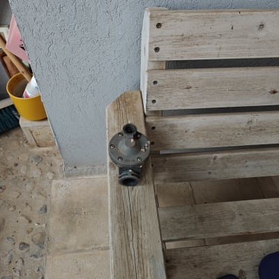 שסתום מתכת על ספסל עץ ליד קיר בטון