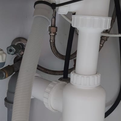 צנרת מתחת לכיור עם חיבורים וצינורות