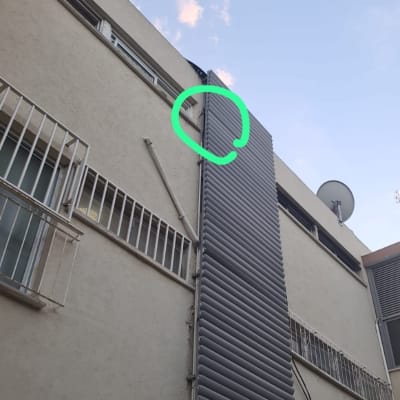 צינור פלסטיק לבן מחובר לקיר בניין