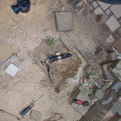 כלי עבודה וצינור מים באדמה רטובה