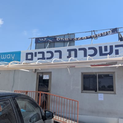 בניין עם שלט השכרת רכבים ושלטים נוספים