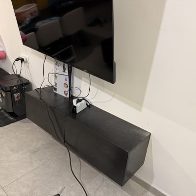 טלוויזיה תלויה על קיר עם כבלים ומדף תחתון