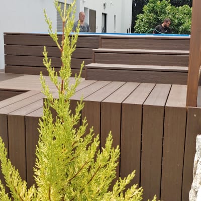 דק עץ חום בגינה עם צמחייה מסביב