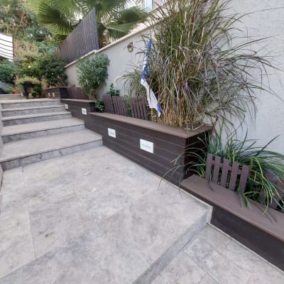 אדניות עץ עם צמחים לאורך שביל מרוצף