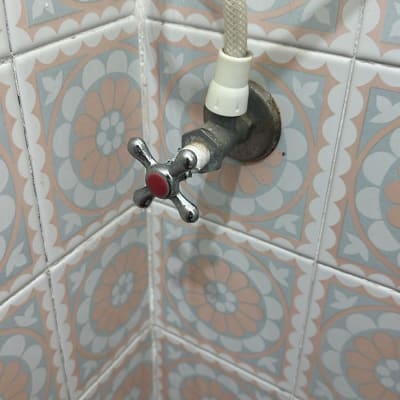 ברז מים עם צינור על רקע אריחים מעוצבים